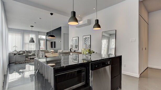 A modern kitchen with a central island, stainless steel appliances, pendant lighting, and a dining area with a sofa and table. - THE BOHO CHIC | Two-Bedroom Loft w. Terrace (Montréal)