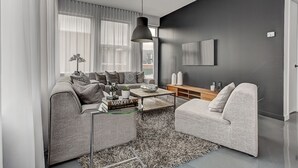 A modern living room with a grey sofa, a coffee table, and a TV on the wall. - THE BOHO CHIC | Two-Bedroom Loft w. Terrace (Montréal)