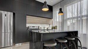 A modern kitchen with a marble island, stainless steel appliances, and bar stools. - THE BOHO CHIC | Two-Bedroom Loft w. Terrace (Montréal)