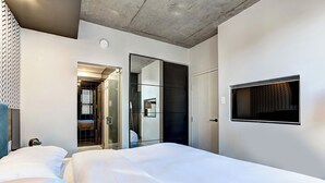 A modern hotel room with a large bed, a TV mounted on the wall, and a sliding door leading to a bathroom. - Modern Apartment with All Amenities (Montreal)