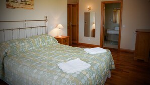 Ein Schlafzimmer mit einem Bett, einem Nachttisch, einer Lampe, einem Spiegel und einer Tür zu einem Badezimmer.