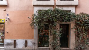 A building with a cobblestone street, a door with graffiti, and a window with a sticker. - Suite Trastevere San Calisto Rome Historical Center  (Roma)