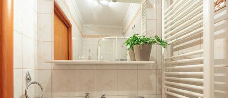 A bathroom with a sink, mirror, towel rack, and a potted plant.
