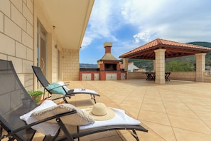 A patio with two lounge chairs, a sun umbrella, and a brick oven. - Apartment Mondo A2 - One Bedroom Apartment, Sleeps 2 (Mokosica)