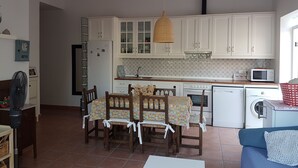 Eine kompakte Küche mit weißen Schränken, einer Mikrowelle, einer Waschmaschine und einem Essbereich mit Tisch und Stühlen.