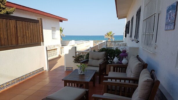 Eine Terrasse mit einem Holztisch, zwei Stühlen, einer Couch und einem kleinen Tisch mit Dekoration.