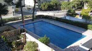 A rectangular swimming pool with a white deck and metal railings, surrounded by greenery and a white fence. - Apartment in Cap Salou Area (Salou)