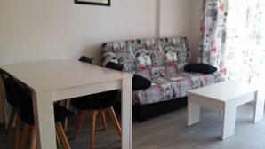 A modern living room with a white dining table, two black chairs, a patterned sofa, and a white coffee table. - Apartment in Cap Salou Area (Salou)