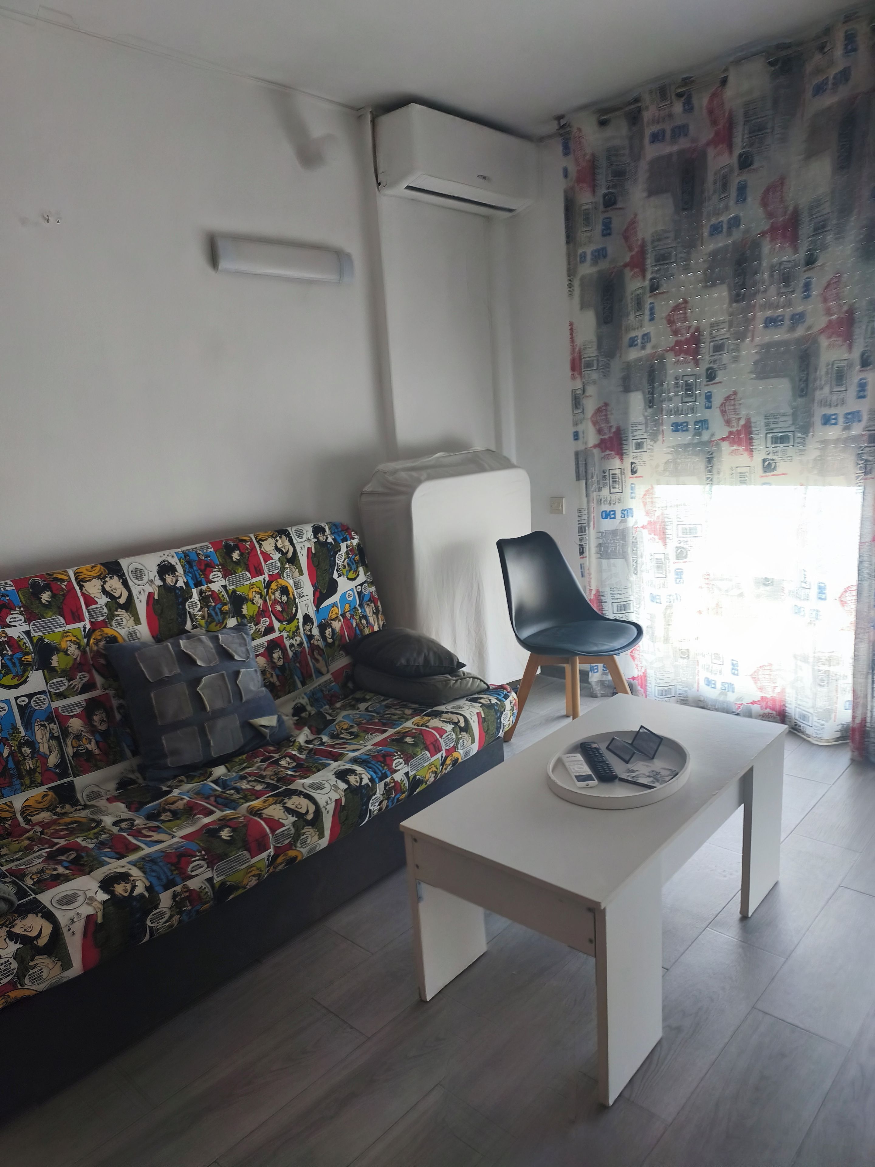 Un salon comprenant un canapé, un fauteuil, une table basse et un appareil de climatisation.