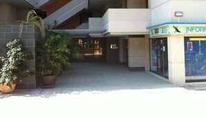 A multi-story building with a ground-level entrance, potted plants, and a sign for an information center. - Apartment in Cap Salou Area (Salou)