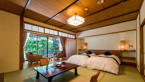 A traditional Japanese-style room with tatami flooring, a low wooden ceiling, and a large window offering a view of greenery outside. - Misasa Onsen MISASAKAN (Misasa)