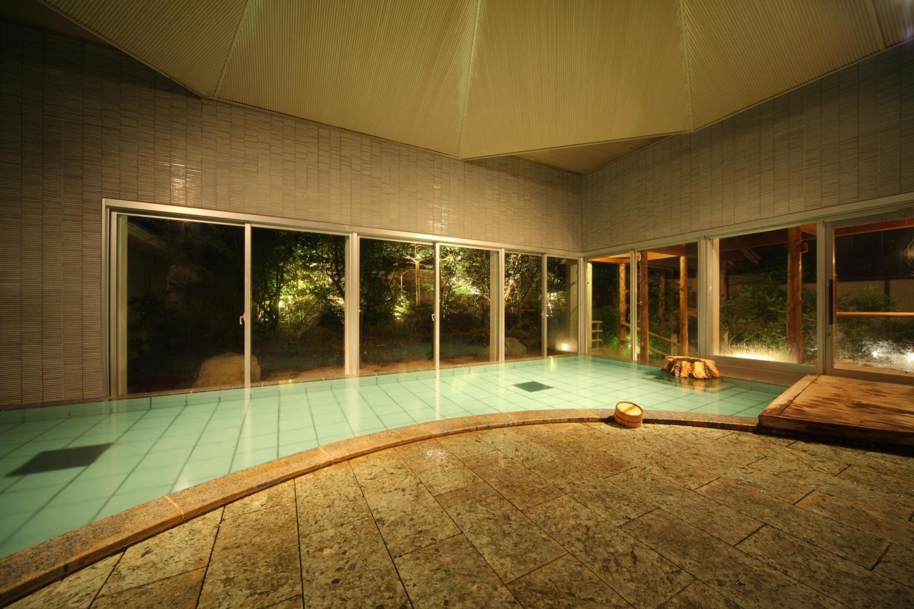 A swimming pool with a tiled floor and a wooden deck area.
