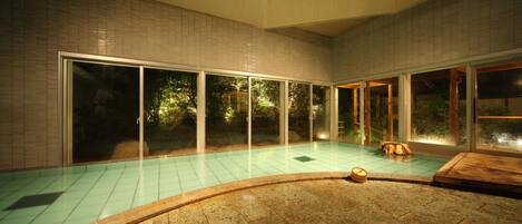 Una piscina con suelo de baldosas y zona de cubierta de madera.