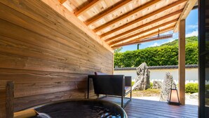 A wooden deck with a hot tub, a chair, and a lantern. - Misasa Onsen MISASAKAN (Misasa)