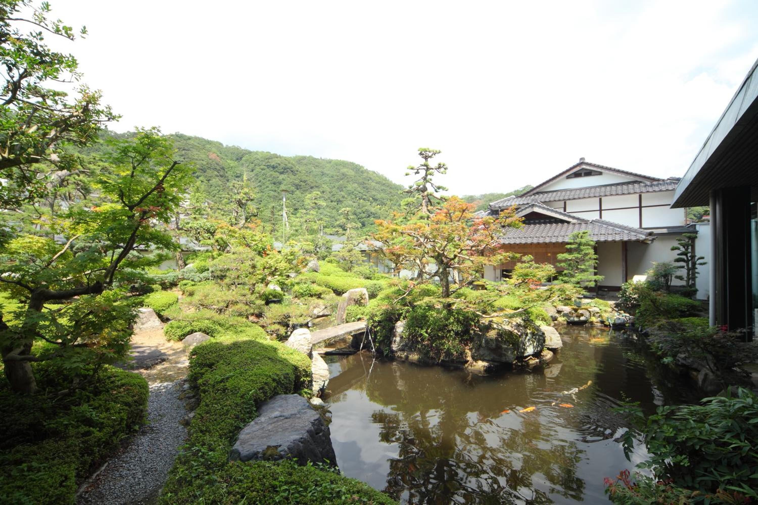 En traditionel japansk have med et spejlbassin, en stenbro og en bygning med et tagdækket af fliser.
