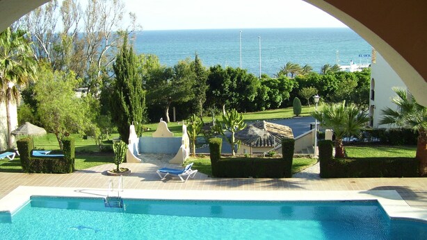 A pool with a view of the sea, surrounded by greenery and a building labeled "EL OCE". - BEAUTIFUL APARTMENT IN TORREOCEANO WITH VIEWS TO THE SEA AND POOLS. (Mijas Malaga (La Cala de Mijas))