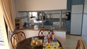 A dining area with a round table, chairs, and a view of the kitchen in the background. - BEAUTIFUL APARTMENT IN TORREOCEANO WITH VIEWS TO THE SEA AND POOLS. (Mijas Malaga (La Cala de Mijas))