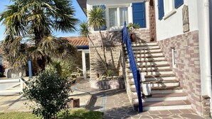 Ein zweistöckiges Haus mit einer Steinstufenanlage, einer Palme und einem kleinen Garten.