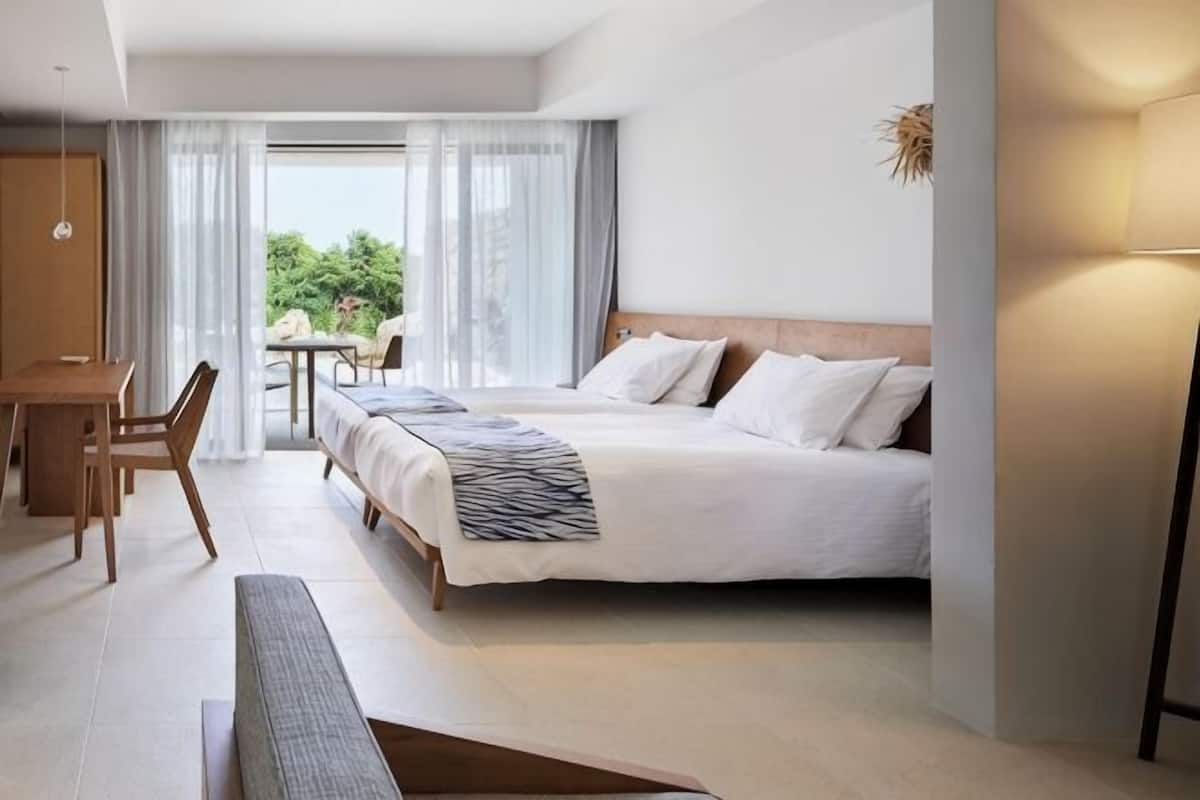Ein Hotelzimmer mit Bett, Schreibtisch, Stuhl und Blick ins Freie.