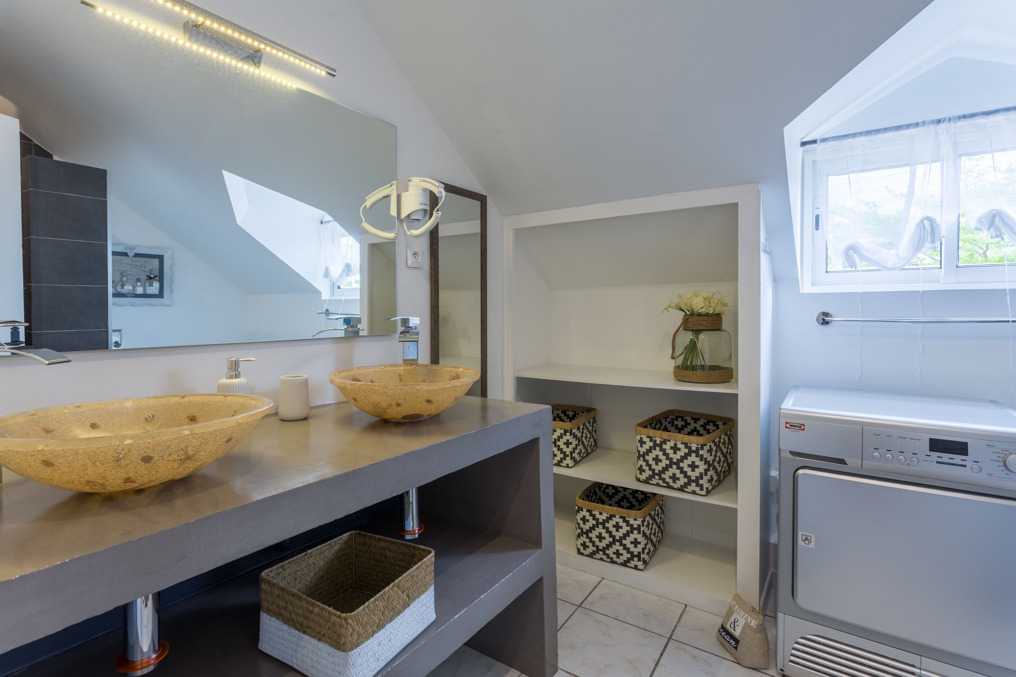 A modern bathroom with two large vessel sinks, a large mirror, and a built-in washing machine.