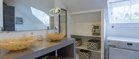 A modern bathroom with two large vessel sinks, a large mirror, and a built-in washing machine.