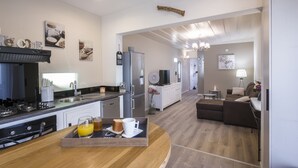 A modern kitchen with a wooden countertop, a dining area with a brown sofa, and a living room with a TV and a lamp. - Large 5 * Villa with heated pool and swimming pool in winter in St Gilles (Saint-Gilles les Bains)