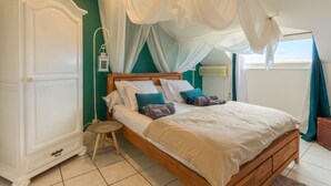 A bedroom with a wooden bed, white canopy, teal walls, and a white wardrobe. - Large 5 * Villa with heated pool and swimming pool in winter in St Gilles (Saint-Gilles les Bains)