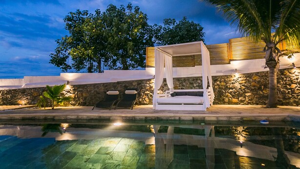 A poolside area with a canopy, stone walls, and a palm tree. - Large 5 * Villa with heated pool and swimming pool in winter in St Gilles (Saint-Gilles les Bains)