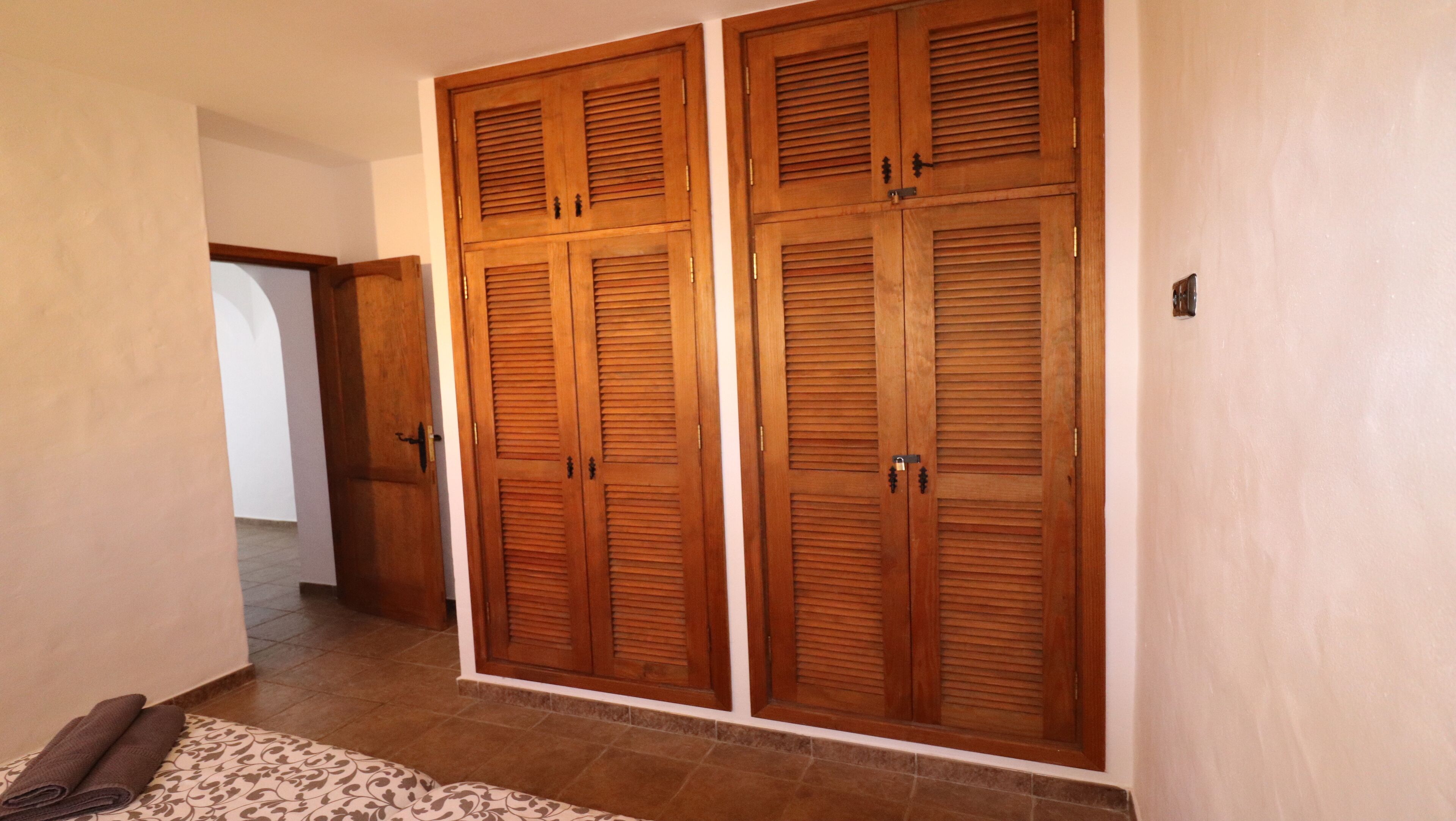 A hallway with wooden double doors and a patterned rug on the floor.