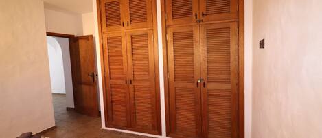 A hallway with wooden double doors and a patterned rug on the floor.