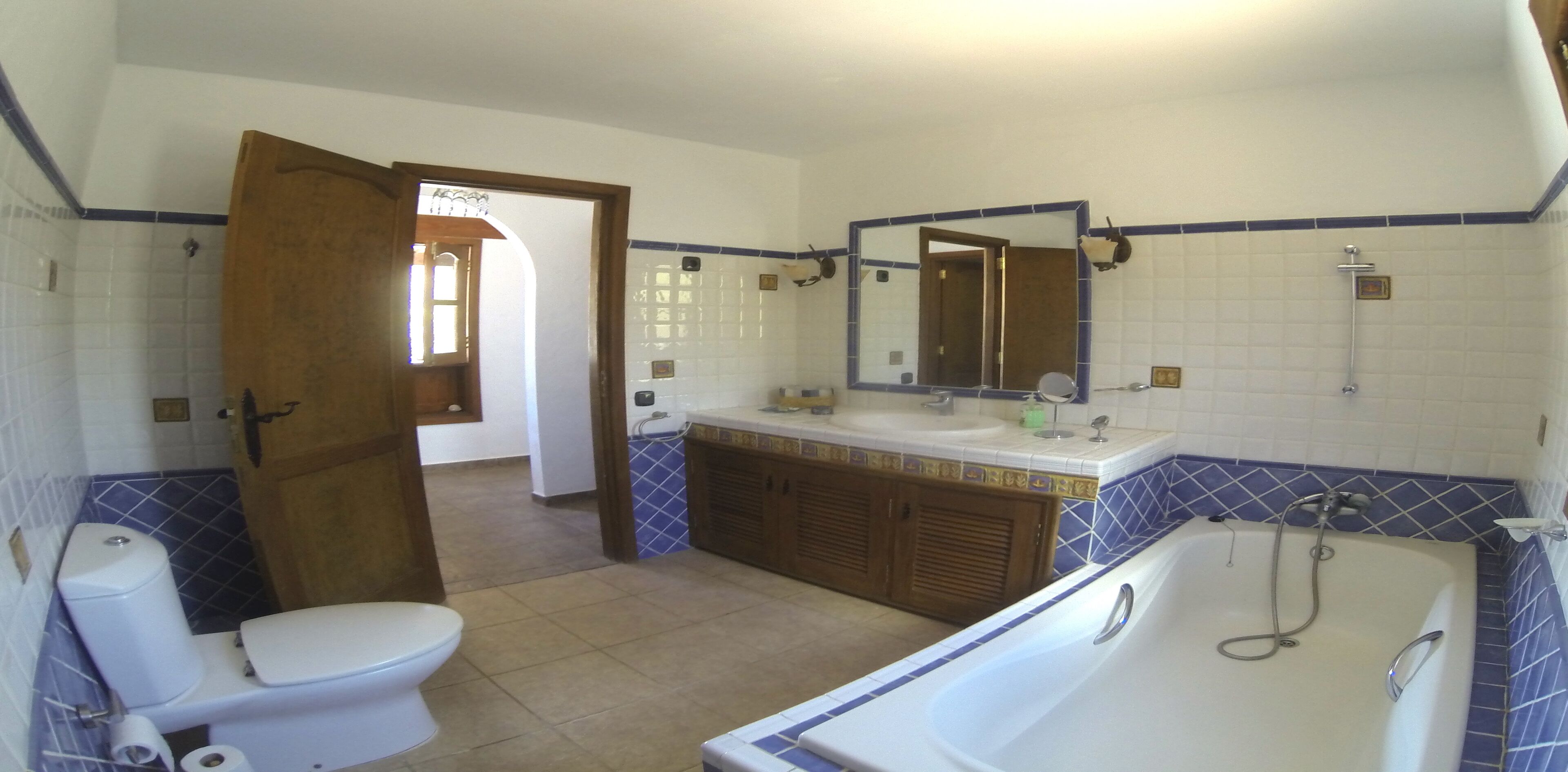 A bathroom with a toilet, sink, bathtub, and a mirror.