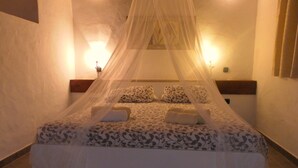 A bedroom with a canopy bed, patterned bedding, and wall-mounted lights.