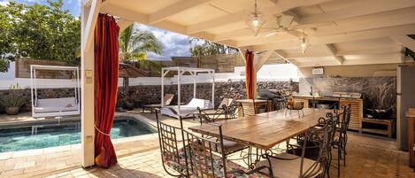 An outdoor patio with a pool, a wooden table, and chairs.
