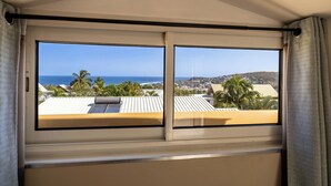 Habitació amb gran finestra que ofereix vistes a l'oceà i una població costanera.