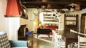A cozy dining area with a wooden table and white chairs, a checkered sofa, and a brick wall with shelves of jars and kitchen utensils. - MANOR HOUSE near Venice, Prosecco hills, and Dolomites with private pool (Codognè)