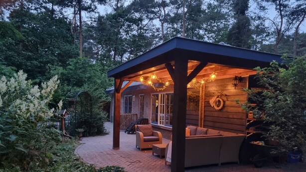 Un espacio de patio cubierto con estructura de madera, mobiliario exterior y un camino de ladrillo.