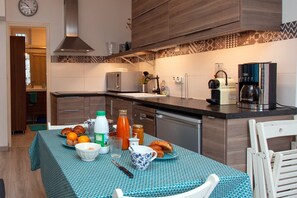Une cuisine avec une table à manger dressée pour le petit-déjeuner, avec des croissants et du jus d’orange.