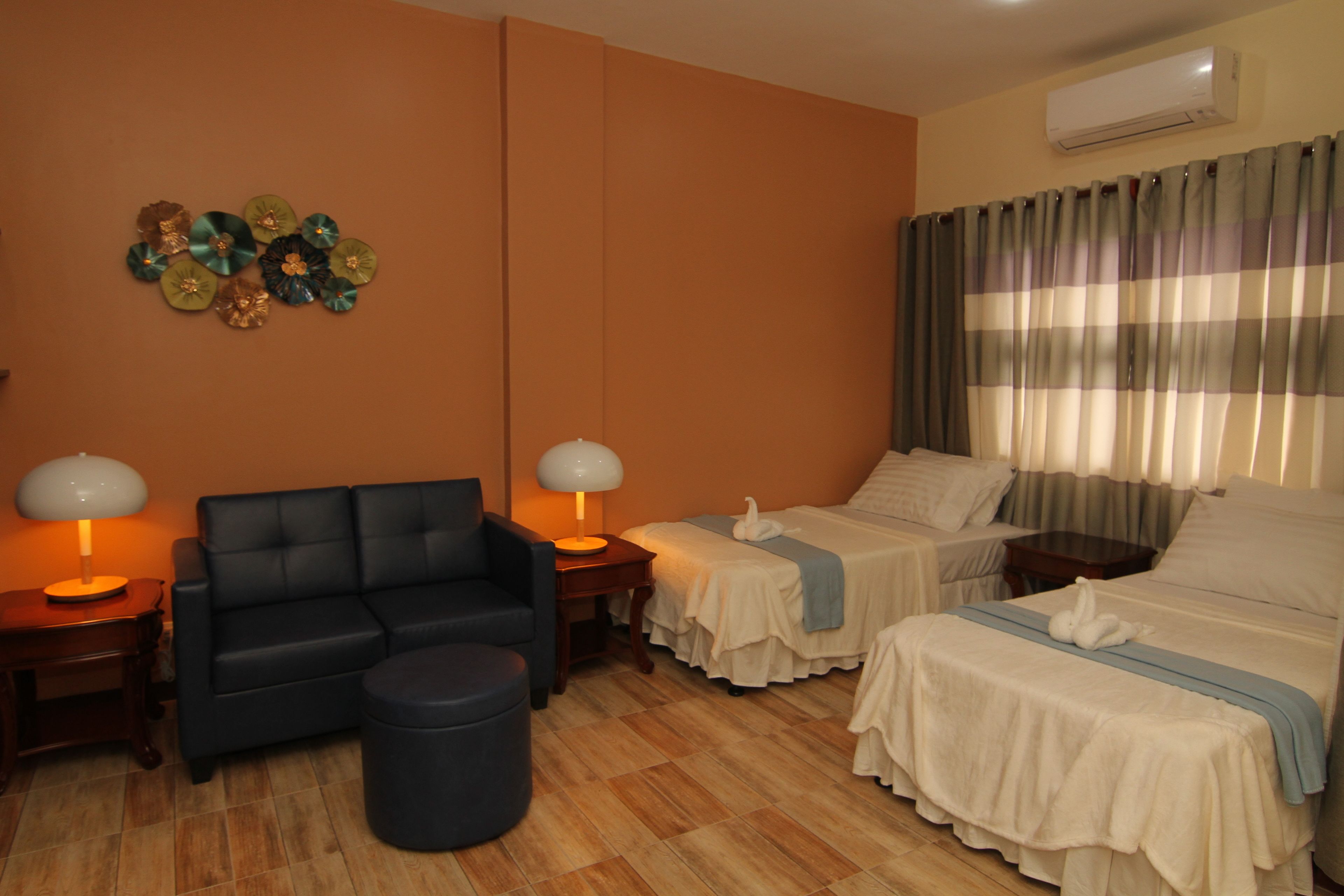 Une chambre d’hôtel avec un canapé, deux lits, une petite table et une lampe.