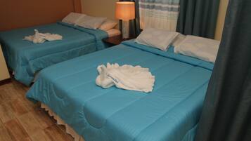 Two twin beds with blue bedding, a bedside table with a lamp, and a towel on each bed.