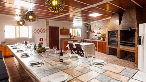Un'ampia cucina con un lungo tavolo da pranzo apparecchiato, un forno a mattoni e lampade moderne.
