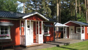 A row of red cabins with white trim, each featuring a porch and a small deck area.