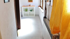 A hallway with a tiled floor, a wooden ceiling, and a white shelf with green bowls. - SEA Studio with Balcony (gornji) (Rovinj)