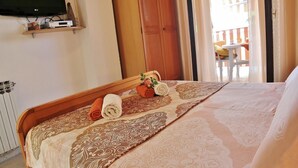 A hotel room with a bed, a TV mounted on the wall, and a view of the outside balcony. - SEA Studio with Balcony (gornji) (Rovinj)