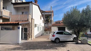 A residential building with a white facade, a balcony with a striped awning, and a parked white car. - SEA Studio with Balcony (gornji) (Rovinj)