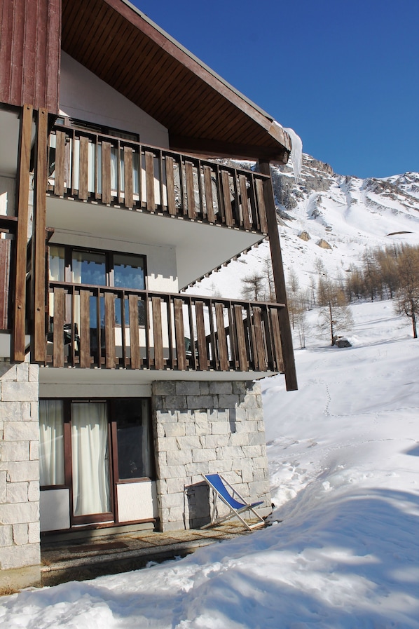 Stunning two-story building with a large ground-floor window and a smaller upper-floor window, set amidst a serene winter landscape.