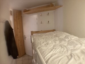 Cozy retreat with a single bed, wooden headboard, and a simple shelf above.