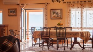 A dining area with a table set for four, a chandelier, and a painting on the wall. - Quinta do Santo by LovelyStay (Santa Cruz)