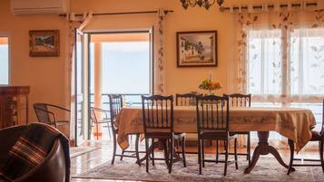 Un coin repas avec une table dressée pour quatre personnes, un lustre et un tableau accroché au mur.