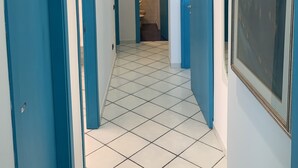 A hallway with blue doors, white tiled floors, and a framed picture on the wall. - Villa Laura PT - directly by the sea (Pizzo)