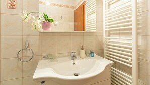 A bathroom with a white sink, a mirror, a potted orchid, and a towel rack. - Mondo Room 1 - One Bedroom Apartment, Sleeps 2 (Mokosica)